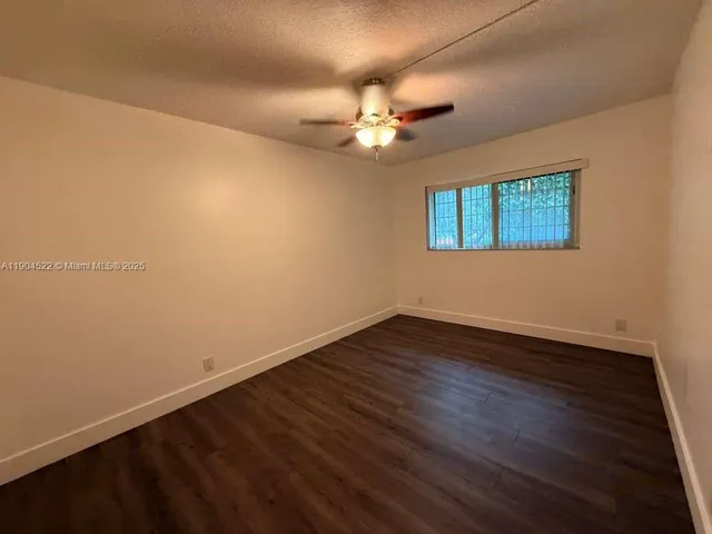 an empty room with wooden floor and fan
