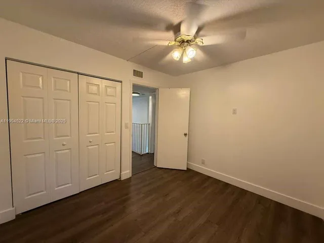 an empty room with wooden floor and ceiling fan