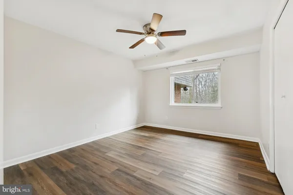 an empty room with wooden floor ceiling fan and windows