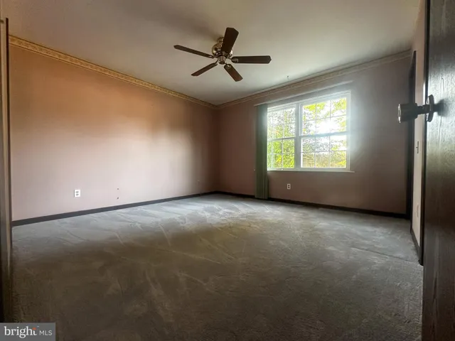 an empty room with windows and ceiling fan