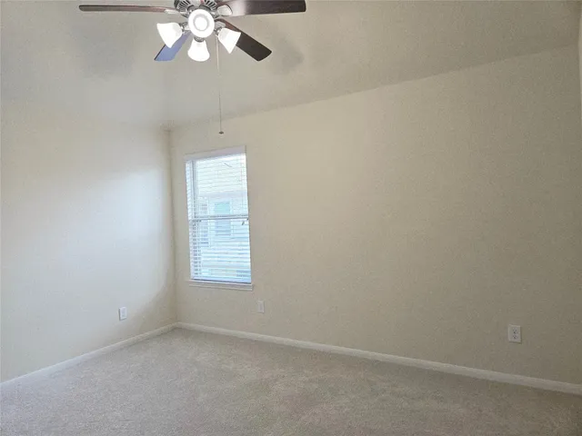 an empty room with a chandelier fan and windows