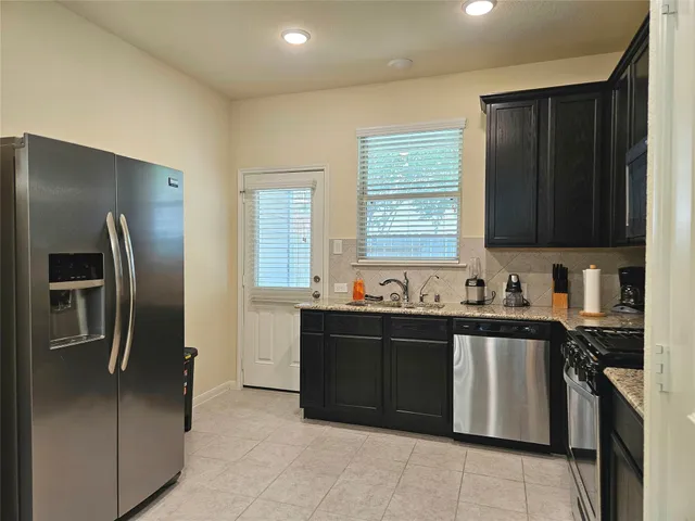 a kitchen with stainless steel appliances granite countertop a refrigerator and a sink