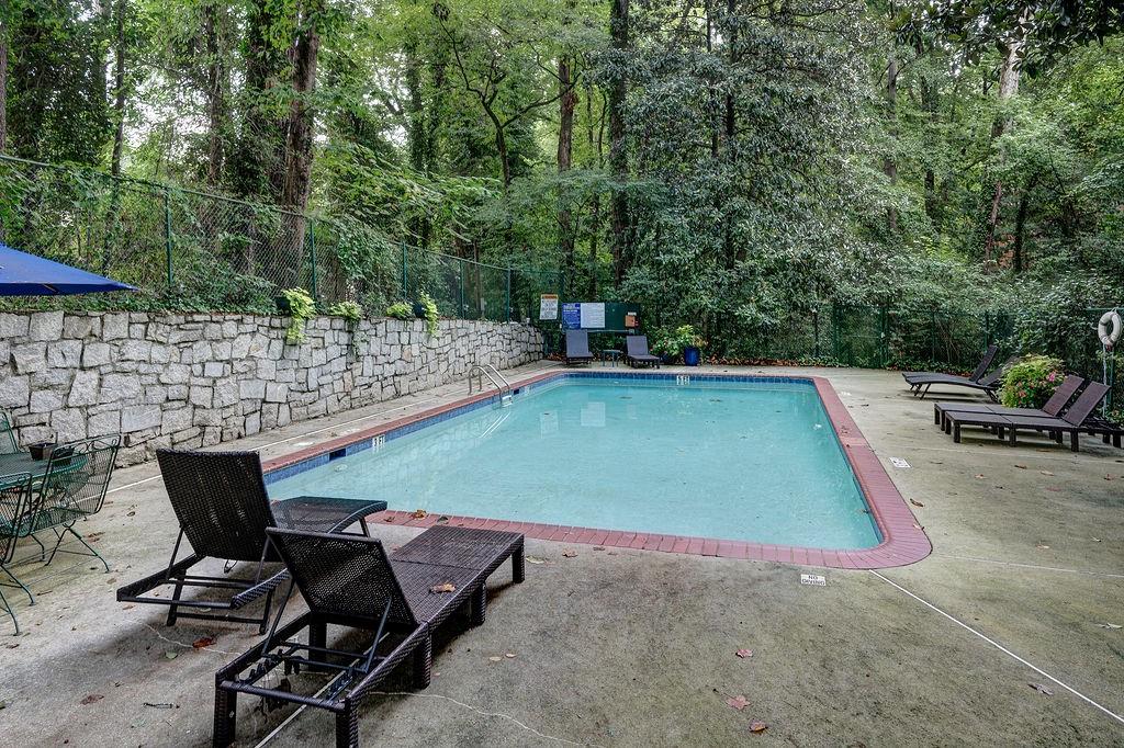 1133 Clairemont Avenue, Unit D Decatur, GA 30030 - Photo 19 of 20 a view of a swimming pool with lawn chairs under an umbrella