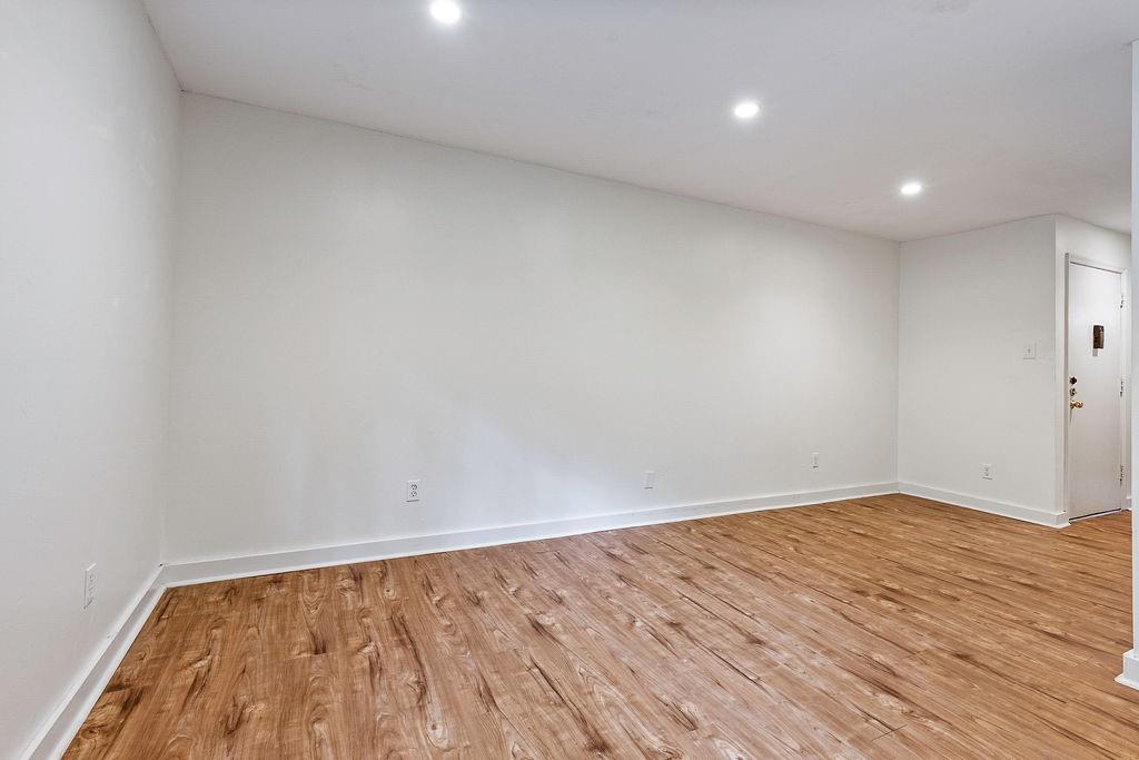 1133 Clairemont Avenue, Unit D Decatur, GA 30030 - Photo 5 of 20 a view of an empty room with wooden floor and a window