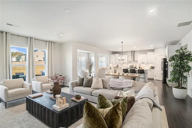 a living room with furniture potted plant and kitchen view