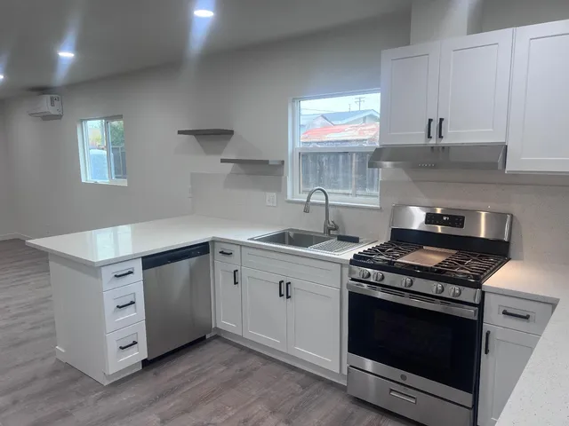 a kitchen with stainless steel appliances a stove a sink and white cabinets