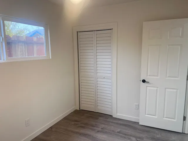 a view of an empty room with wooden floor and closet