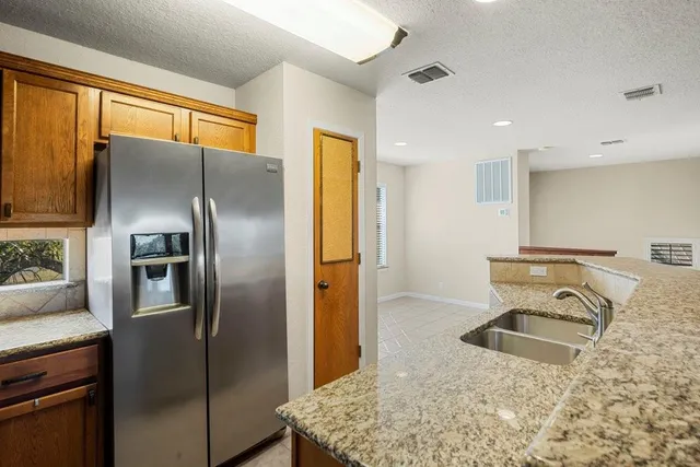 a kitchen with stainless steel appliances granite countertop a refrigerator and a sink