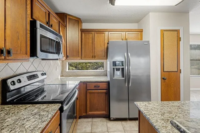 a kitchen with granite countertop a sink stove and refrigerator