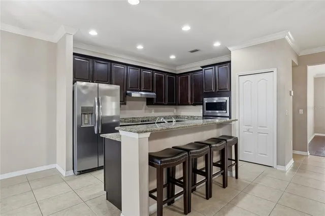a kitchen with stainless steel appliances granite countertop a table chairs refrigerator and microwave