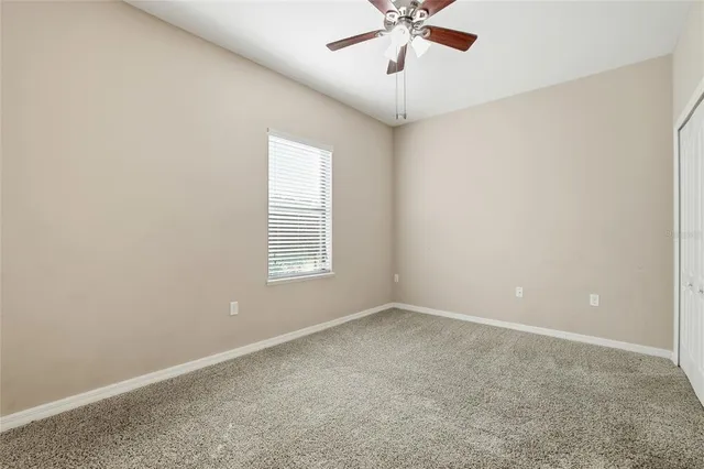 en empty room with windows and chandelier fan