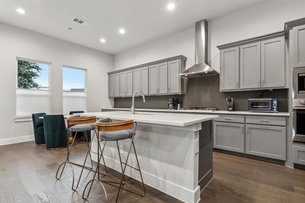 4109 Maison Ridge Dallas, TX 75219 - Photo 7 of 39 Kitchen with a center island with sink, gray cabinets, wall chimney exhaust hood, and sink