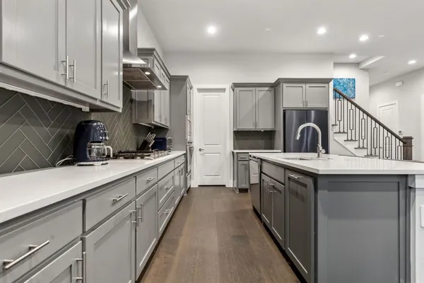 a kitchen with stainless steel appliances granite countertop a sink a stove and a wooden floors