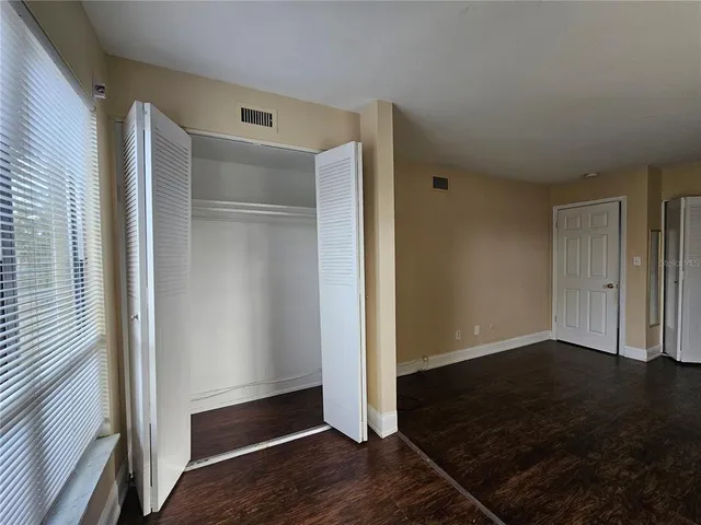 an empty room with wooden floor door and windows