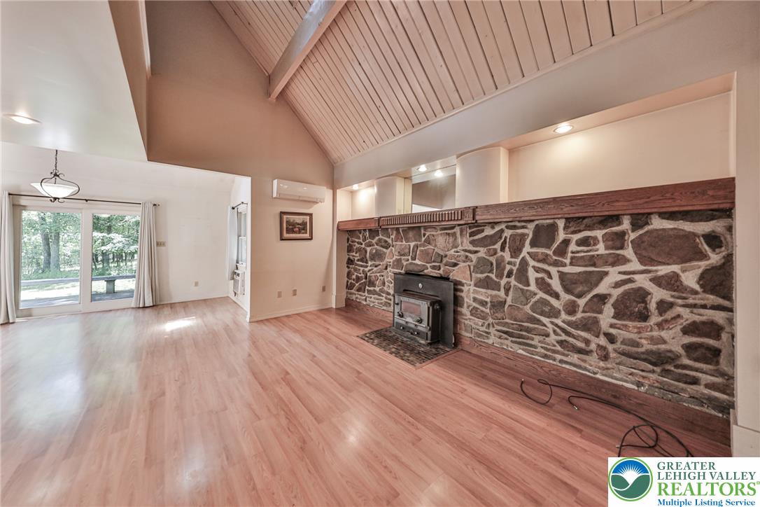 152 Inverhouse Road Henryville, PA 18332 - Photo 27 of 64 A spacious living area featuring a stone fireplace and vaulted wood-paneled ceilings.