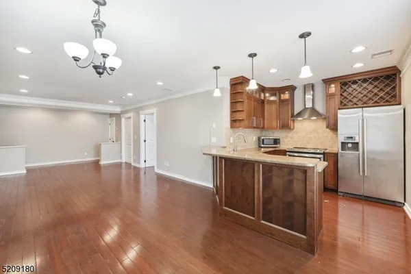 a kitchen with stainless steel appliances granite countertop a refrigerator a sink dishwasher a stove and a dining table with wooden floor