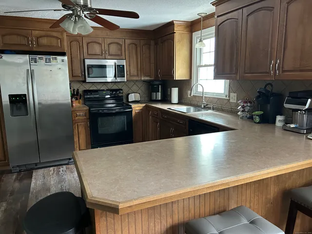 a kitchen with stainless steel appliances granite countertop a refrigerator a stove and a sink with wooden floor