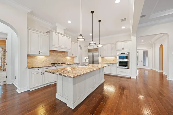 a kitchen with stainless steel appliances granite countertop a wooden floor sink stove and cabinets