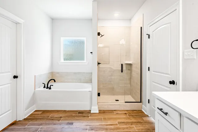 a bathroom with a tub shower sink and mirror