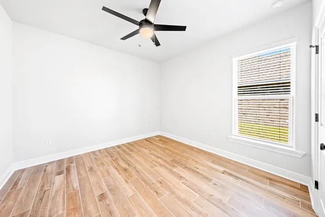 an empty room with a window and a ceiling fan