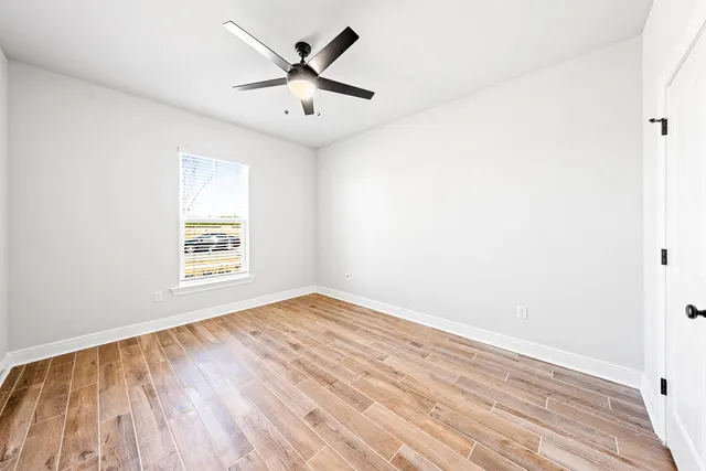 an empty room with wooden floor and windows
