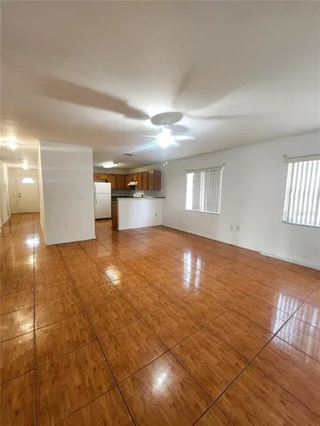 a view of empty room with wooden floor and fan