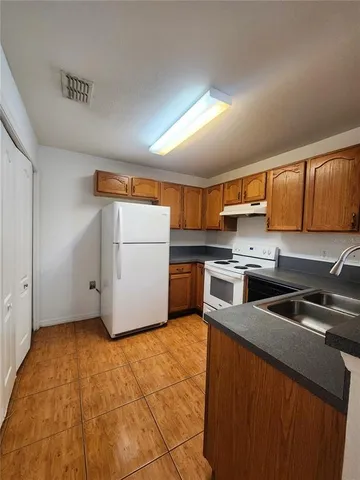 a kitchen with a refrigerator sink and wooden cabinets