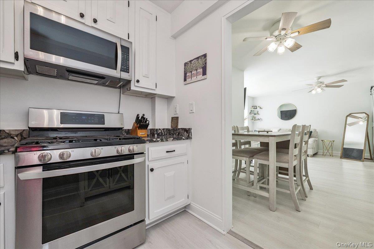 700 Shore Road, Unit 2E Long Beach, NY 11561 - Photo 22 of 31 a kitchen with stainless steel appliances a stove a microwave a dining table and chairs