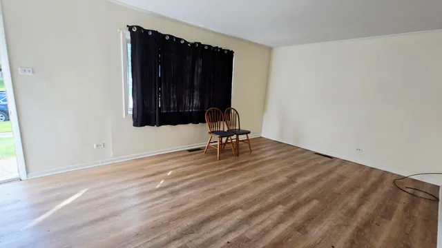 a view of a livingroom with wooden floor and a bench