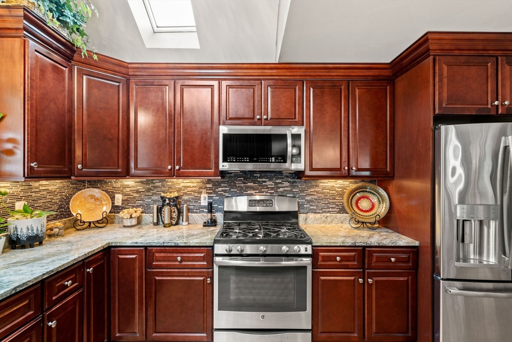 5 Comanche Circle, Unit 5 Haverhill, MA 01835 - Photo 6 of 29 a kitchen with stainless steel appliances wooden cabinets and a stove top oven