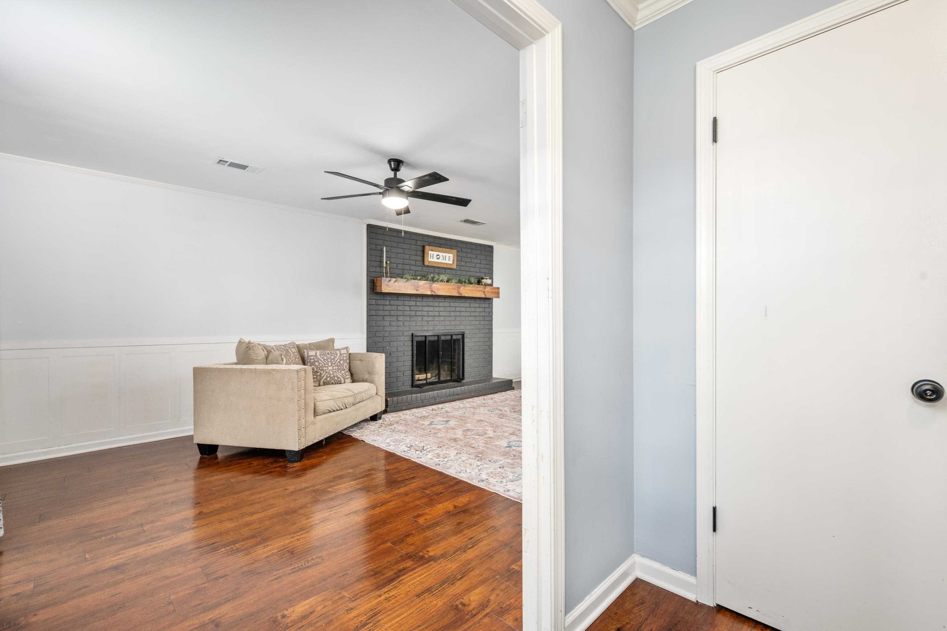 608 King Ridge Cove Collierville, TN 38017 - Photo 3 of 32 Living area featuring crown molding with smooth ceilings, wood floors, a brick wood burning fireplace, and ceiling fan
