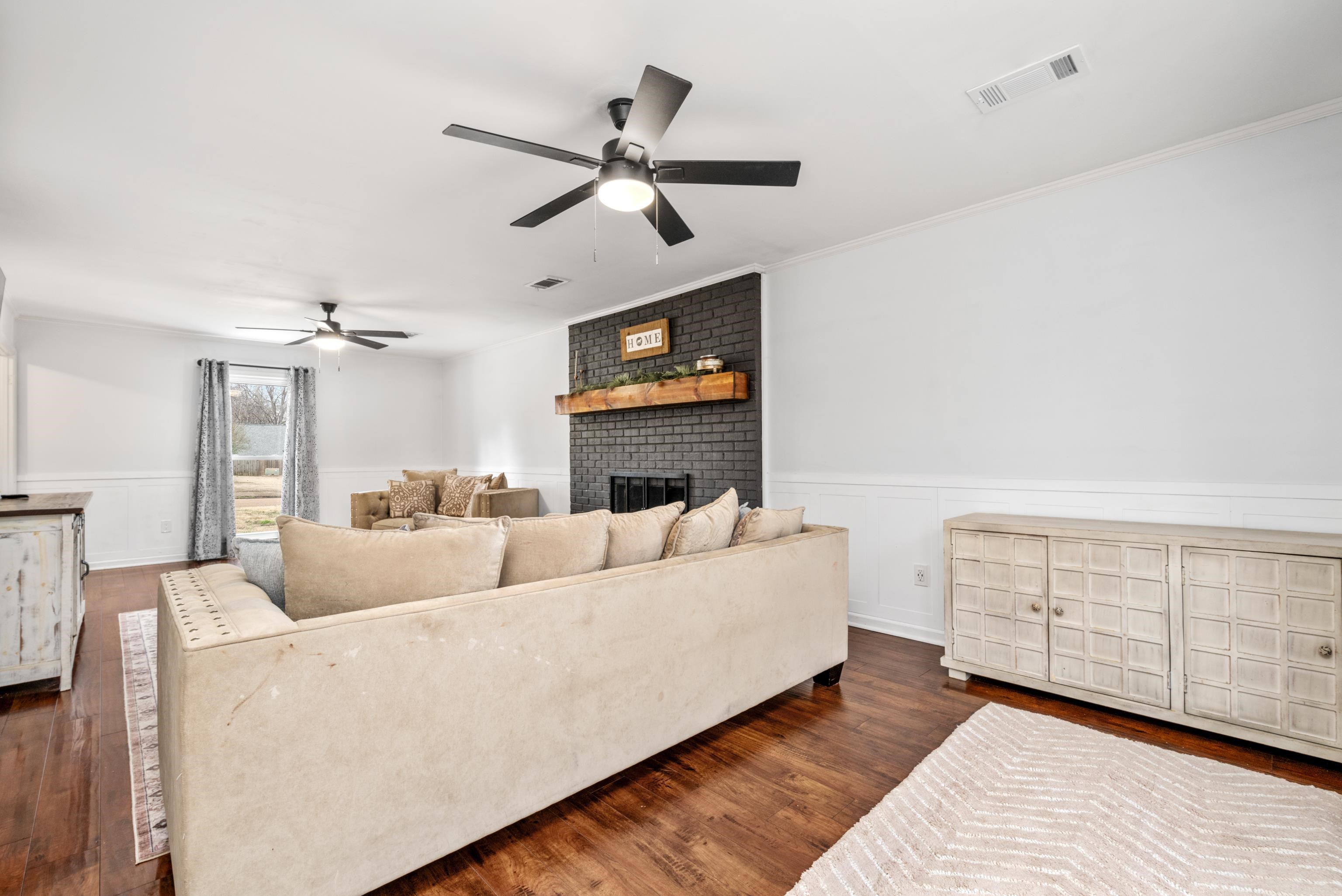 608 King Ridge Cove Collierville, TN 38017 - Photo 5 of 32 Living area featuring wainscoting, dark wood flooring, ceiling fan, a fireplace, and crown molding