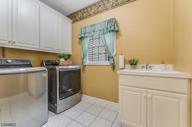 a utility room with stainless steel appliances white cabinets and a sink