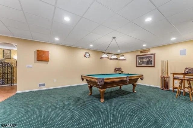 a living room with pool table and a wooden floor