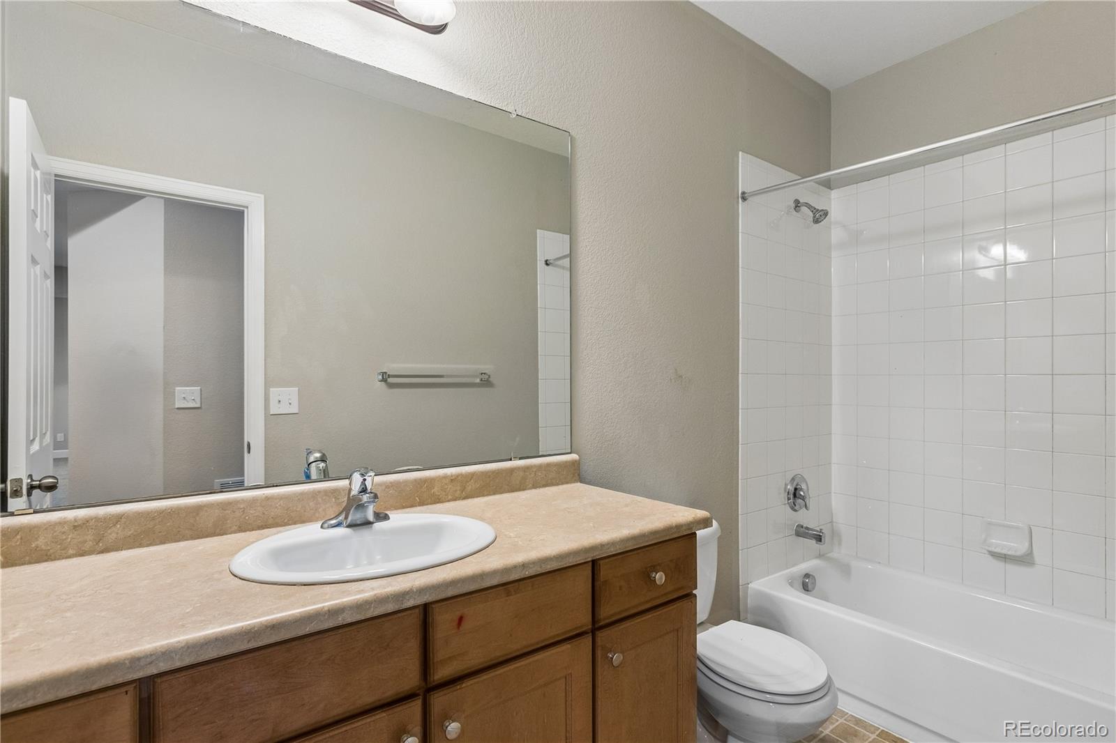 5031 South Rome Street Aurora, CO 80015 - Photo 36 of 39 a bathroom with a granite countertop sink toilet a mirror and shower