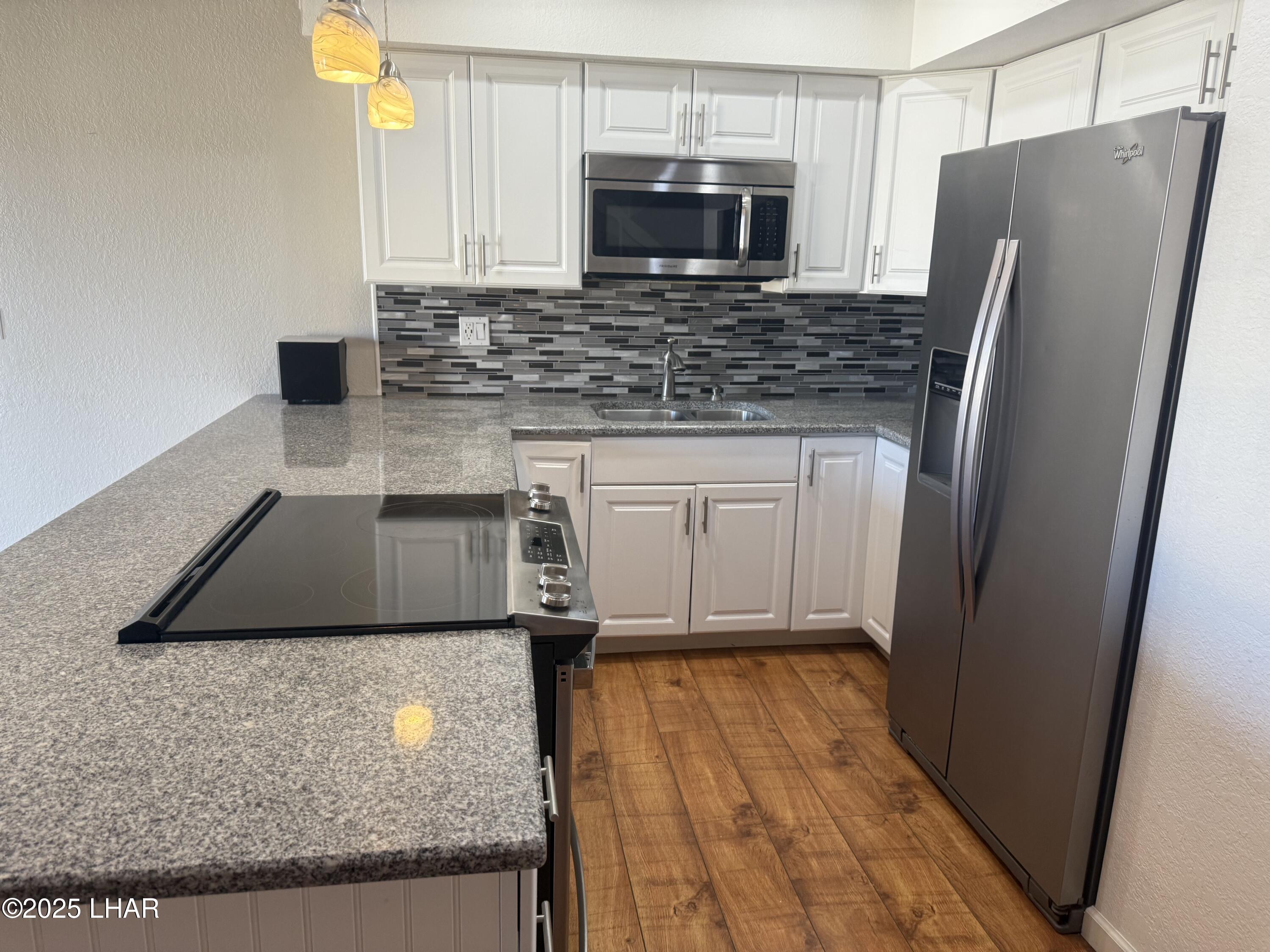 8625 Riverside Drive, Unit 38 Parker, AZ 85344 - Photo 14 of 48 a kitchen with stainless steel appliances granite countertop a refrigerator a stove and a microwave with wooden floor