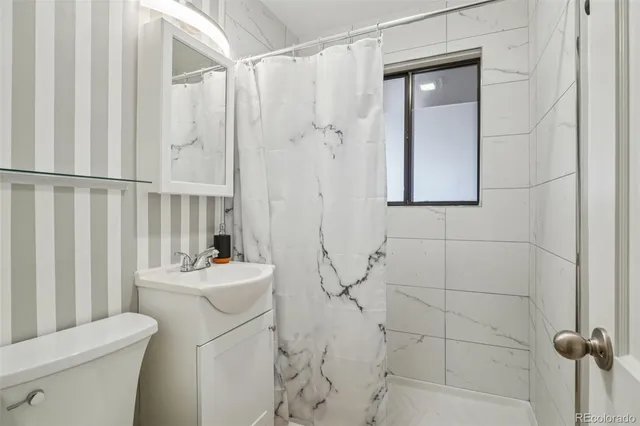 a bathroom with a sink a toilet and shower curtain