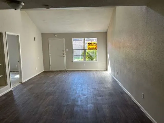 an empty room with a window and wooden floor