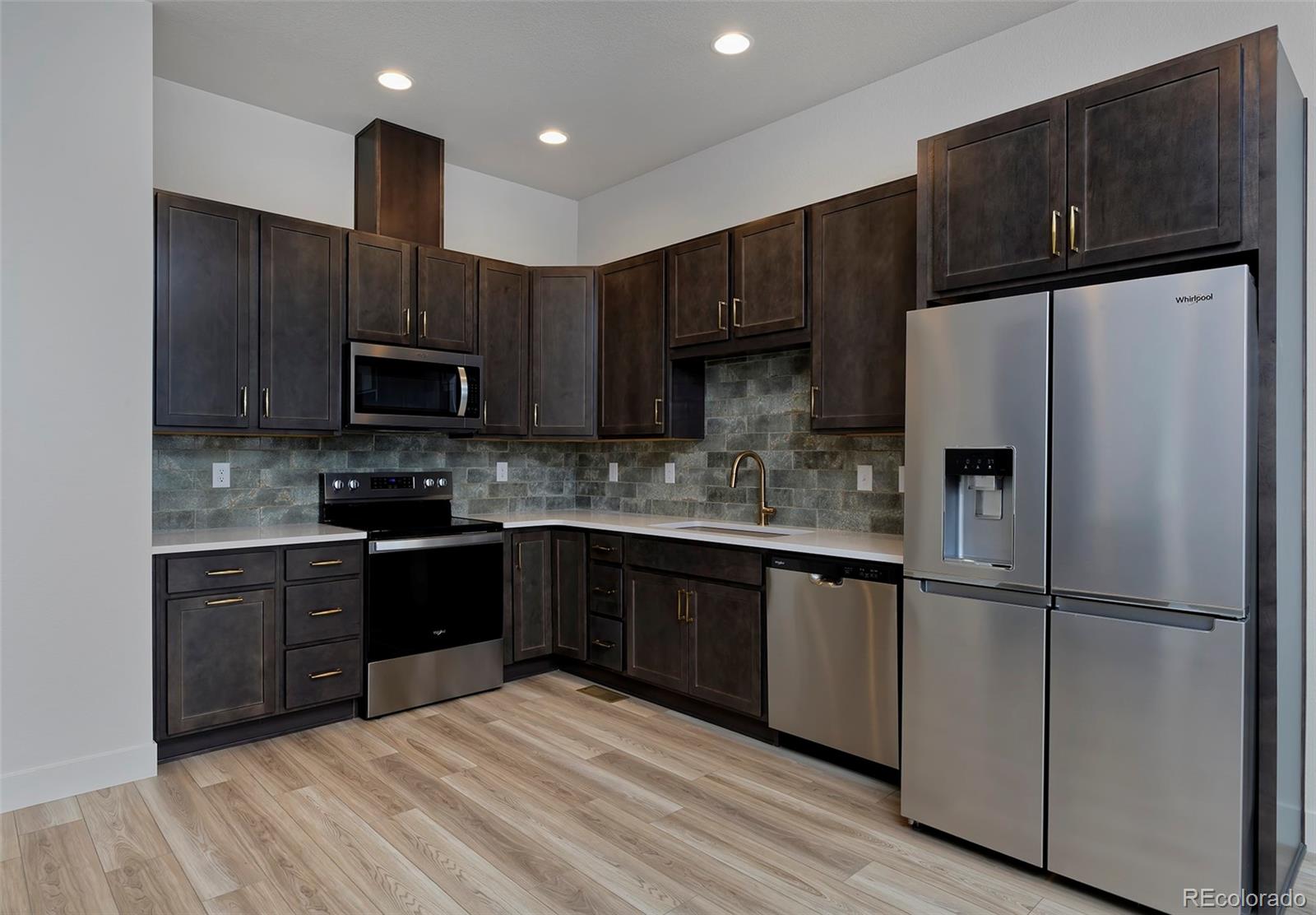 3136 West Bonfils Place Denver, CO 80236 - Photo 13 of 43 a kitchen with stainless steel appliances wooden cabinets and granite counter tops
