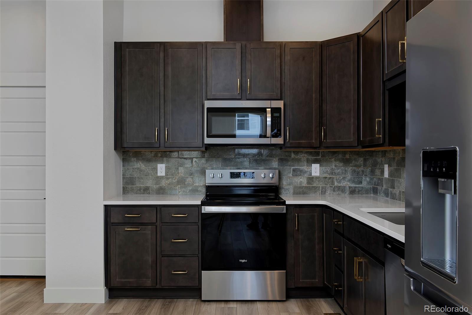 3136 West Bonfils Place Denver, CO 80236 - Photo 14 of 43 a kitchen with granite countertop a stove and a microwave