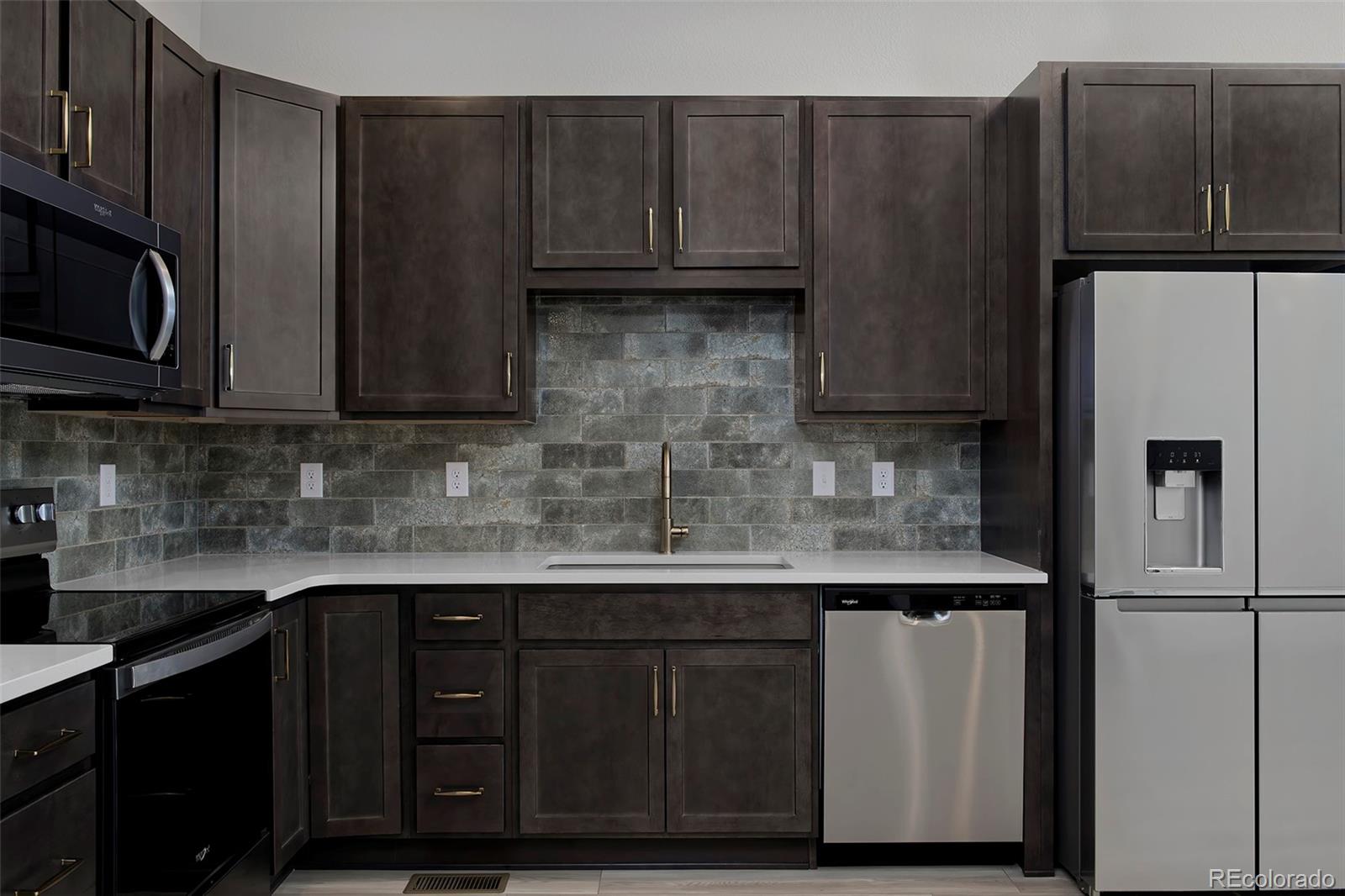 3136 West Bonfils Place Denver, CO 80236 - Photo 15 of 43 a kitchen with granite countertop wooden cabinets a refrigerator and a sink