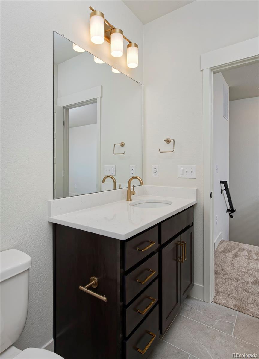 3136 West Bonfils Place Denver, CO 80236 - Photo 29 of 43 a bathroom with a sink a toilet and a mirror