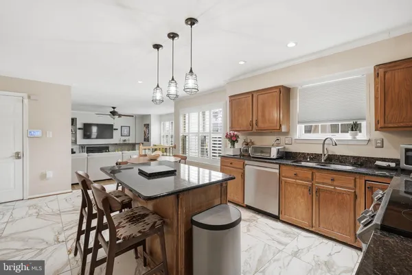 a kitchen with stainless steel appliances granite countertop a stove top oven a sink a dining table and chairs with wooden floor
