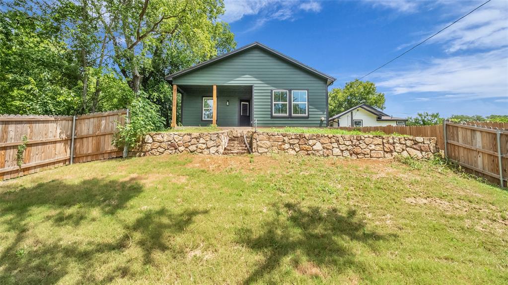716 East Chestnut Street Denison, TX 75021 - Photo 23 of 26 Expansive backyard with a manicured lawn, full wood fencing, and a stone retaining wall