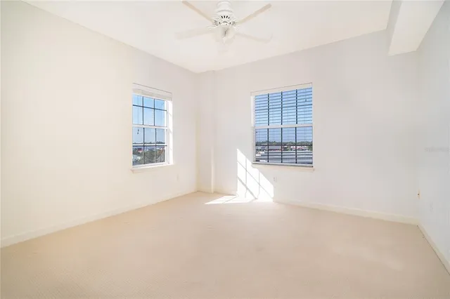 an empty room with windows and fan