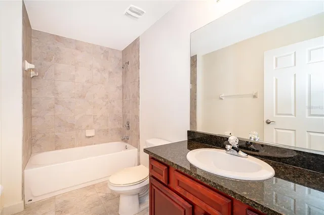 a bathroom with a granite countertop sink toilet mirror and bathtub