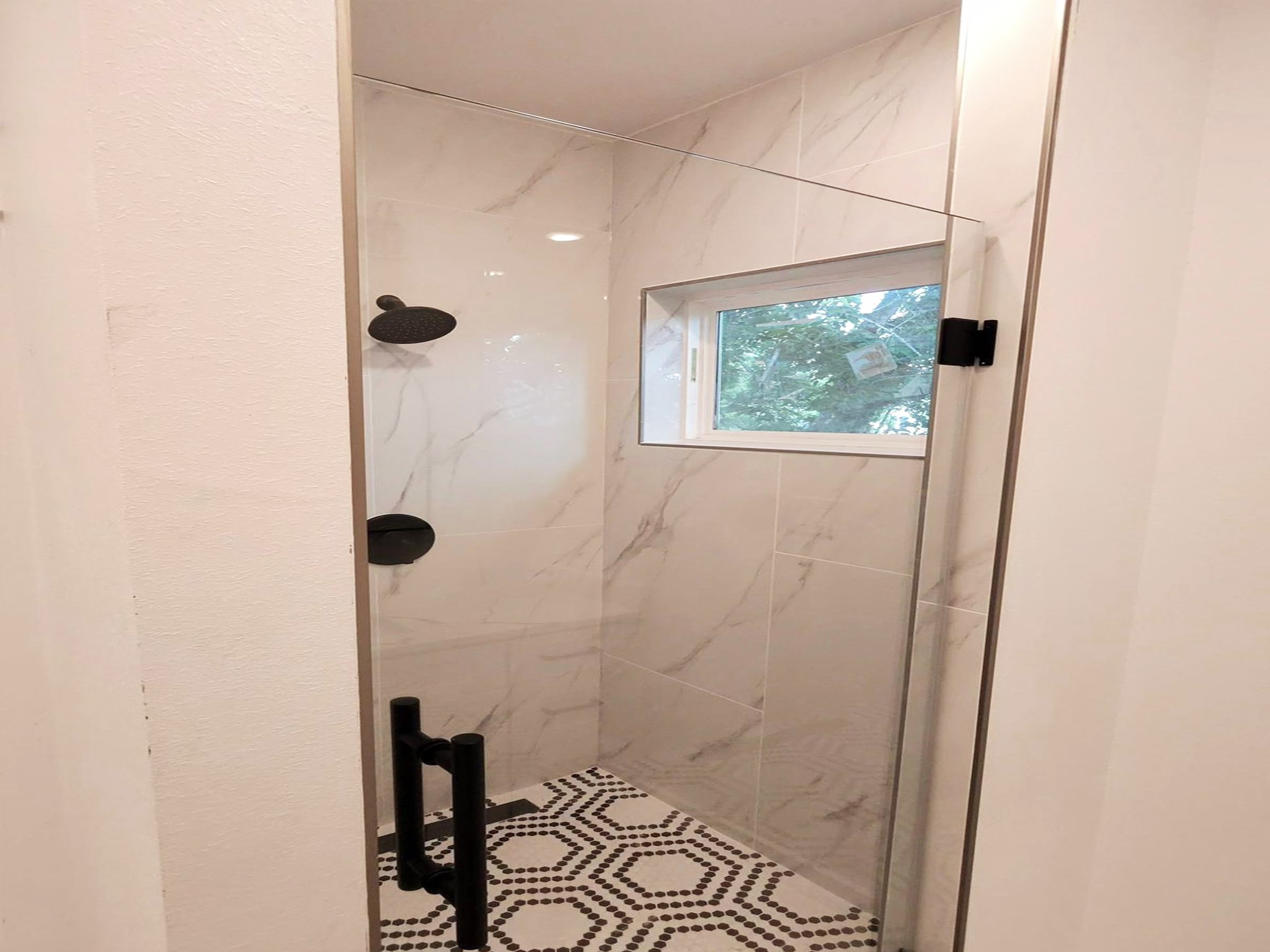 6747 Liverpool Street Houston, TX 77021 - Photo 8 of 18 The primary bathroom includes a spacious shower and a large overhead window that fills the room with natural light.