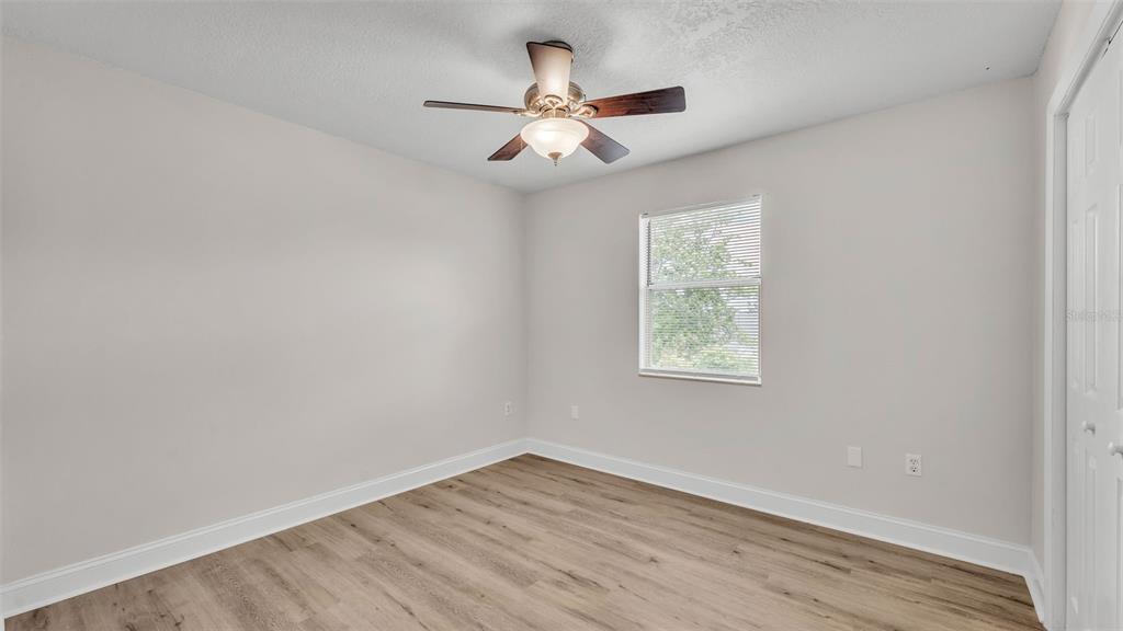 3806 Bent Tree Loop West Lakeland, FL 33813 - Photo 12 of 58 an empty room with wooden floor ceiling fan and windows