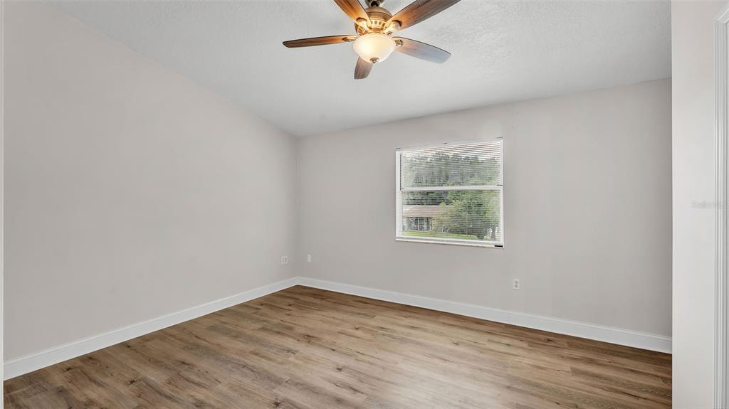 3806 Bent Tree Loop West Lakeland, FL 33813 - Photo 14 of 58 an empty room with wooden floor chandelier fan and windows