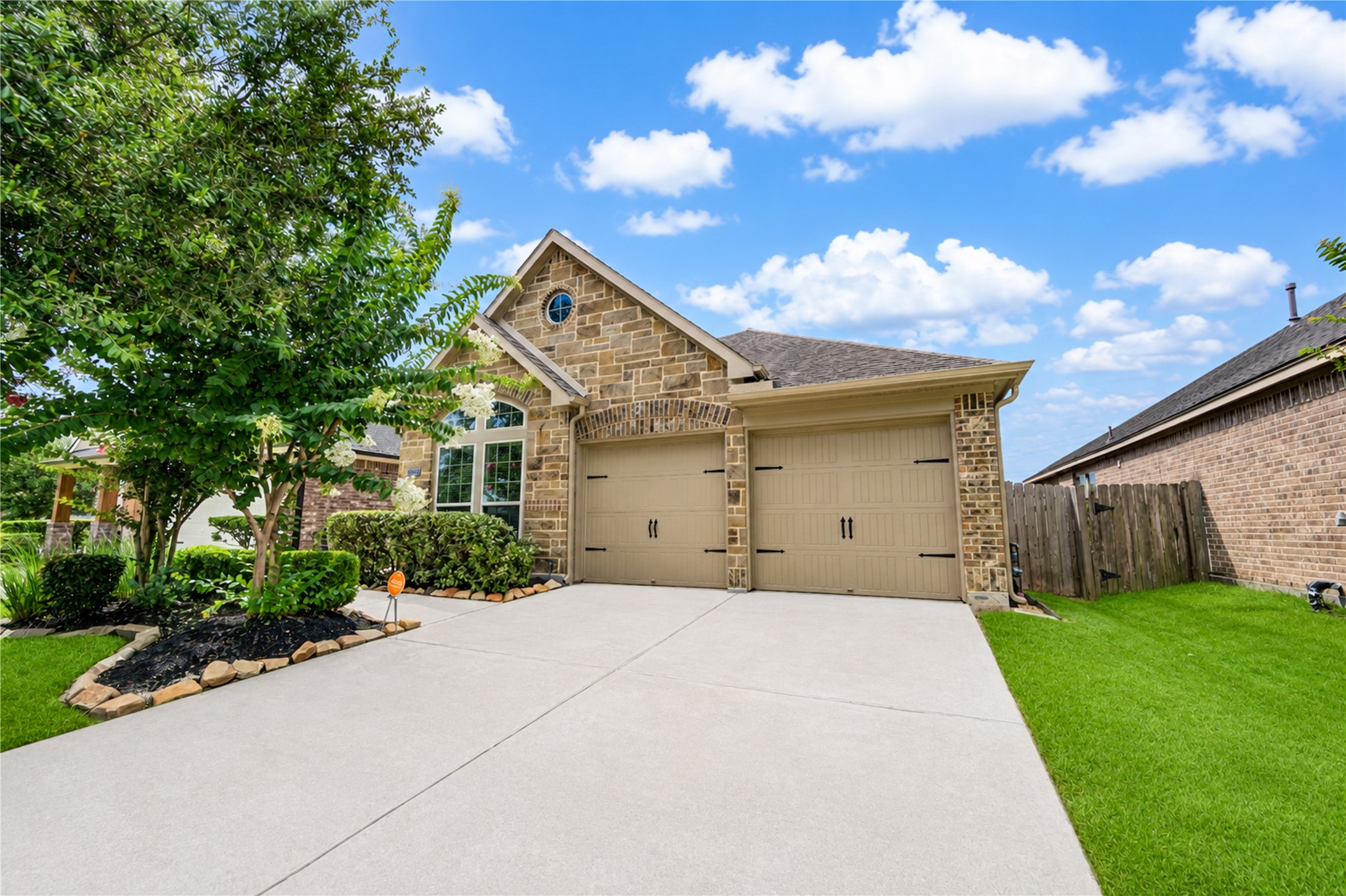 27407 Gatlin Lane Spring, TX 77386 - Photo 2 of 35 Exceptional curb appeal begins with manicured landscaping, mature shade trees, and a pristine lawn that reflects the meticulous care this home has received. The attractive brick and stone elevation, oversized driveway, and beautifully maintained exterior create a warm first impression in the highly desirable Spring Trails community. Truly move-in ready, this home stands out from the moment you arrive.